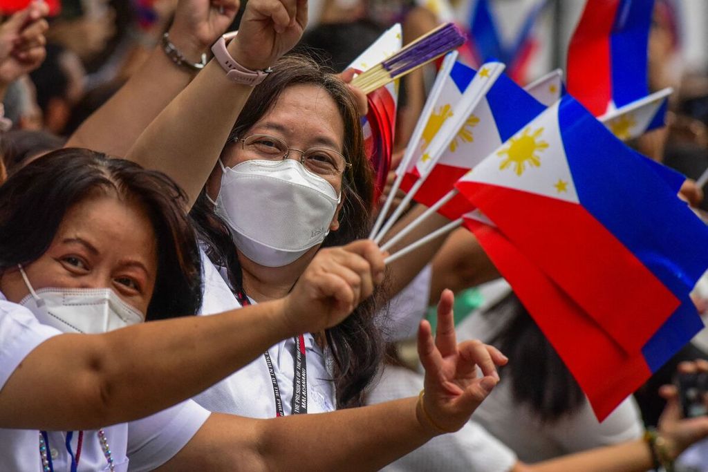 Pegawai negeri Filipina melambaikan bendera nasional Filipina jelang pelantikan presiden baru Filipina, Ferdinand Marcos Jr, di Manila pada Kamis (30/6/2022).