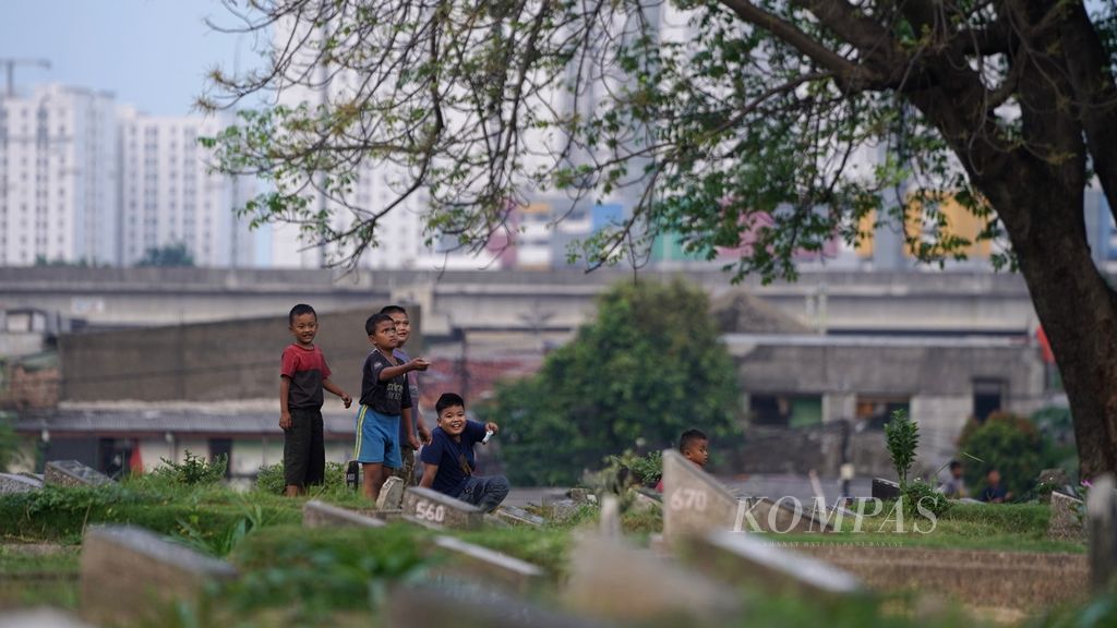 Anak-anak bermain layang-layang di Tempat Pemakaman Umum (TPU) Kober Jatinegara, Kelurahan Rawa Bunga, Jakarta Timur, Sabtu (3/6/2023). Minimnya tempat bermain di hunian padat penduduk membuat makam menjadi pilihan untuk beraktivitas warga. 