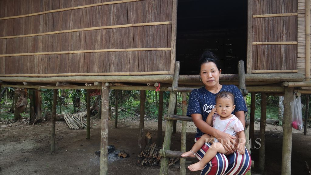Seorang perempuan menggendong anaknya di depan rumah tradisional Talang Mamak di Dusun Begayoan, Desa Rantau Langsat, Kecamatan Batang Gansal, Kabupaten Indragiri Hulu, Riau, Jumat (29/7/2022).