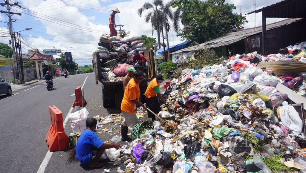 Petugas kebersihan mengangkut sampah dari tempat pembuangan sampah sementara di Kecamatan Gedongtengen, Kota Yogyakarta, Rabu (23/12/2020). Banyak sampah melebar hingga separuh badan jalan.