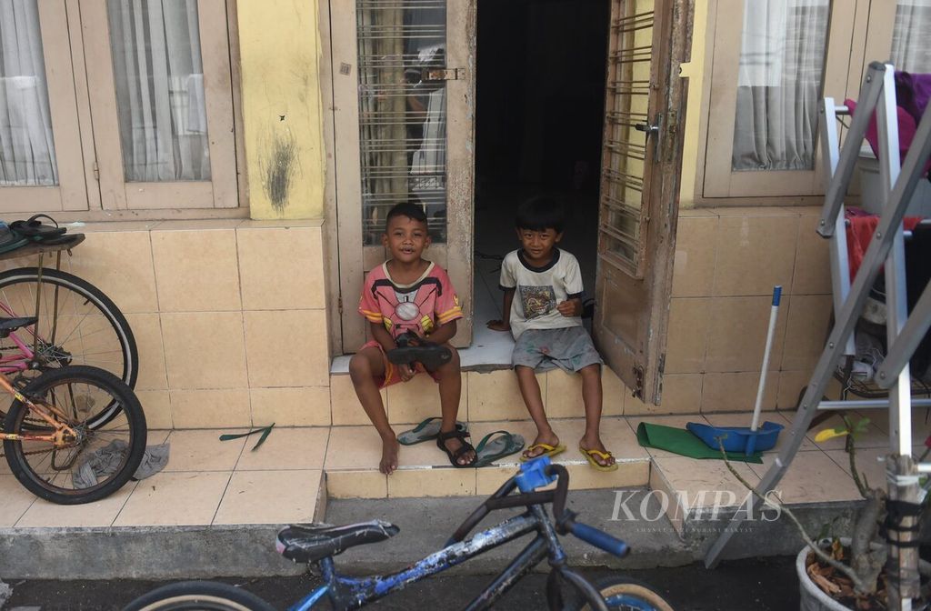 Dua anak duduk di depan rumahnya di Kampung Pandean, Surabaya, Jawa Timur, Rabu (5/7/2023). Sejumlah kampung di pinggir Sungai Kalimas masih menampakkan wajah Surabaya pada masa lalu. Bangunan-bangunan tua masih ada dan difungsikan sebagai tempat tinggal, walau banyak dari bangunan tersebut kondisinya memprihatinkan. 
