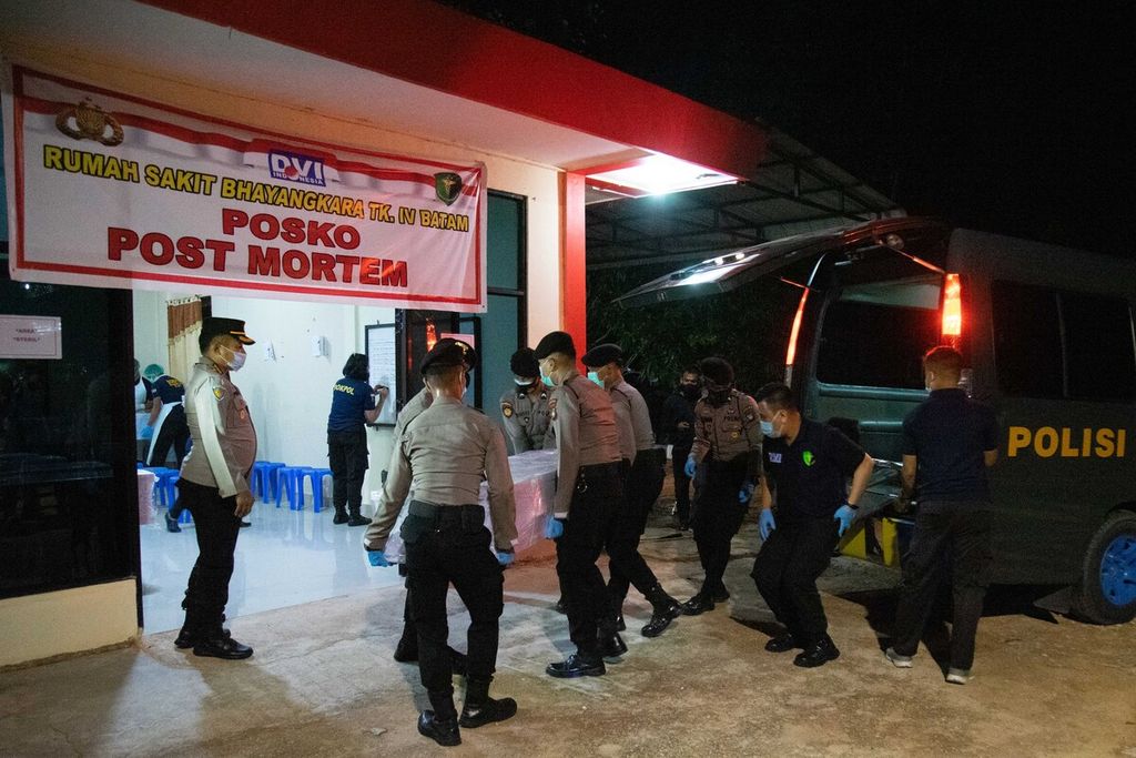 Polisi menurunkan satu jenazah pekerja migran di posko <i>post mortem </i>Rumah Sakit Bhayangkara Polda Kepulauan Riau, Kamis (23/12/2021). 
