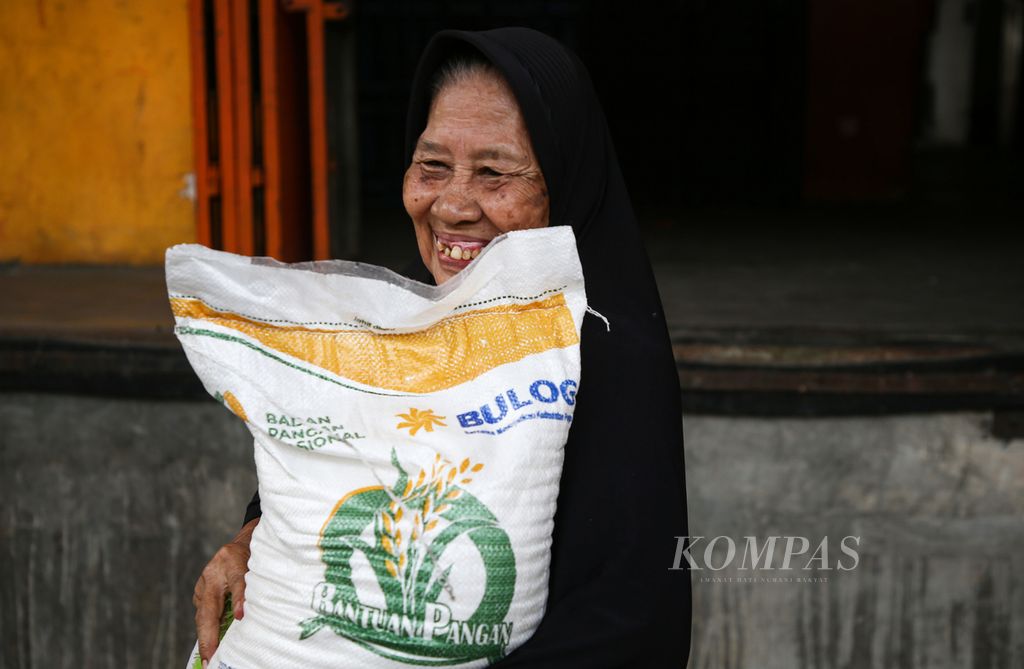 Seorang perempuan tersenyum saat menerima bantuan sosial beras di Kantor Pos Tanjung Priok, Jakarta Utara, Selasa (19/09/2023). Beras bantuan seberat 10 kilogram tersebut dirasakan sangat membantu warga di tengah harga beras yang tinggi. 