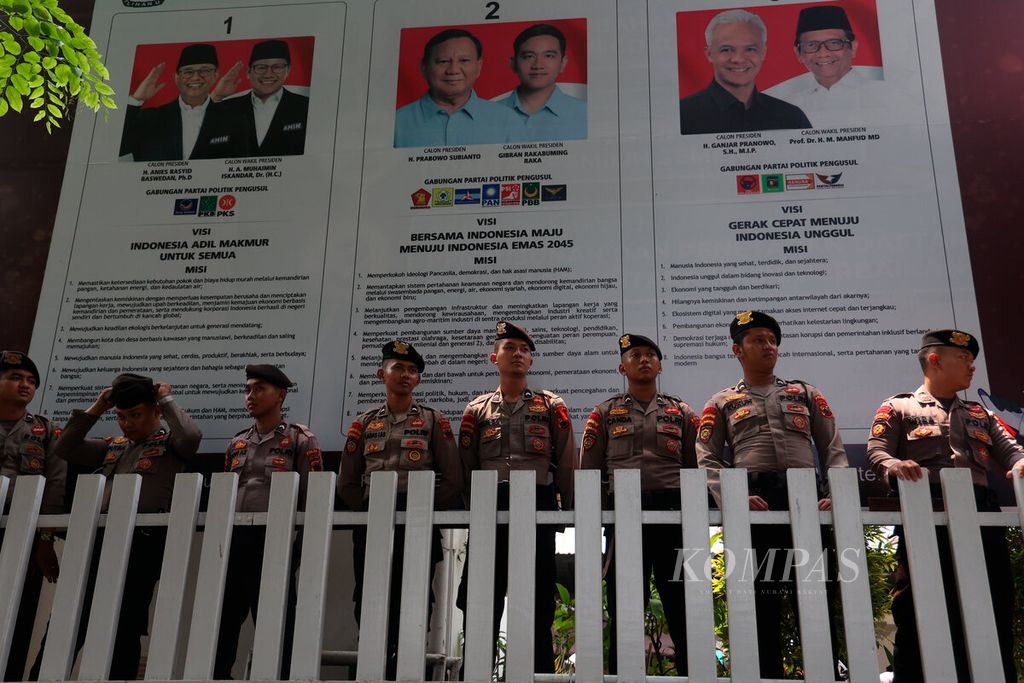 Polisi berjaga dengan latar belakang foto calon presiden saat berlangsungnya aksi unjuk rasa di depan Kantor Komisi Pemilihan Umum Jawa Tengah di Kota Semarang, Rabu (21/2/2024). 