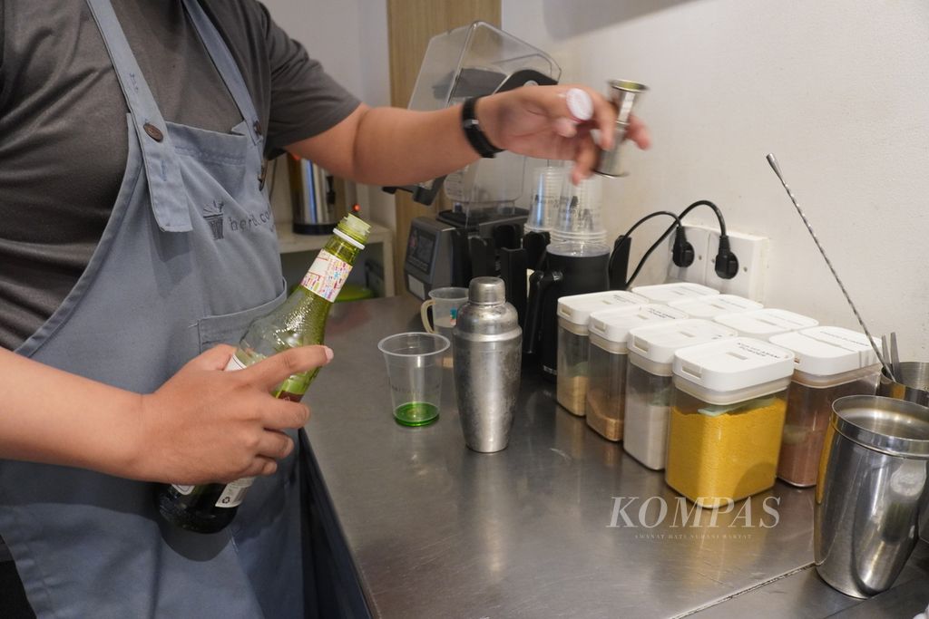 Pekerja menuangkan sirup pandan untuk dikocok bersama jamu beras kencur di sebuah kafe jamu di Kecamatan Semarang Tengah, Kota Semarang, Jawa Tengah, Selasa (11/6/2024). Di kafe tersebut, jamu diolah menjadi minuman kekinian, seperti jamu <i>blend</i> (diblender), jamu <i>shake</i> (kocok), hingga es krim jamu. Jamu dihadirkan secara unik dan menarik untuk memikat pembeli berusia muda.