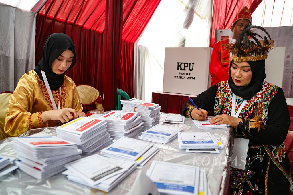 Petugas KPPS mengenakan pakaian adat daerah saat menyiapkan dokumen pemilu di TPS 118, Pulo Gebang, Cakung, Jakarta Timur, Rabu (14/2/2024).  