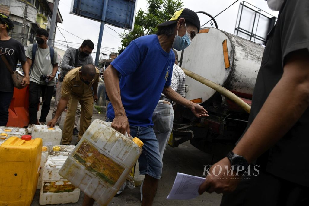Pekerja membawa jeriken yang telah diisi minyak goreng curah dalam pendistribusian untuk pedagang di Pasar Anyar, Kota Tangerang, Banten, 29 Maret 2022. 