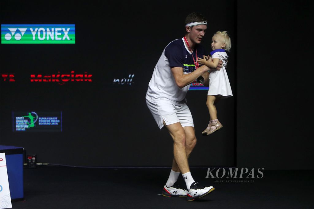 Pebulu tangkis Denmark, Viktor Axelsen, menyambut anaknya, Vega Rohde Axelsen, yang ikut naik ke podium saat pemberian medali dan hadiah untuk juara East Ventures Indonesia Terbuka 2022 di Istora Gelora Bung Karno, Jakarta, Minggu (19/6/2022). 