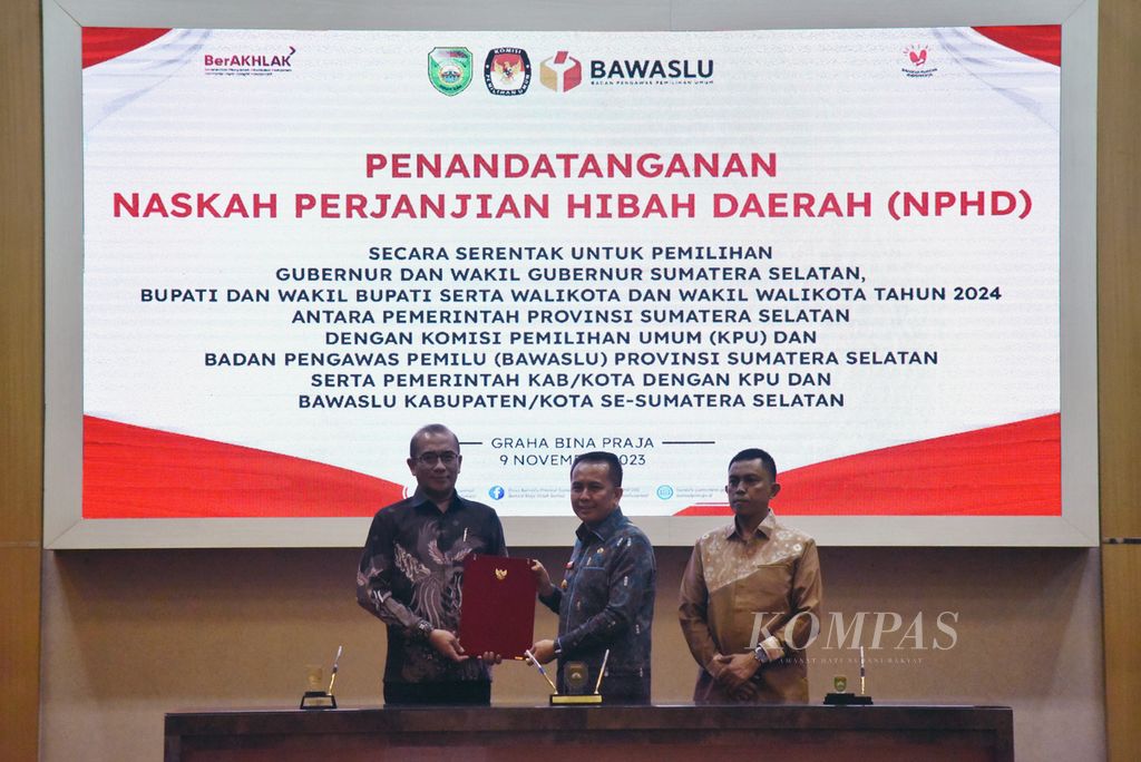 Ketua Komisi Pemilihan Umum Hasyim Asy'ari (kiri) menerima dokumen dari Penjabat Gubernur Sumatera Selatan Agus Fatoni (tengah) disaksikan Ketua Badan Pengawas Pemilu Sumsel Kurniawan (kanan) usai penandatanganan "Naskah Perjanjian Hibah Daerah (NPHD) untuk Penyelenggaraan Pilkada Serentak Tahun 2024" di Palembang, Kamis (9/11/2023). 