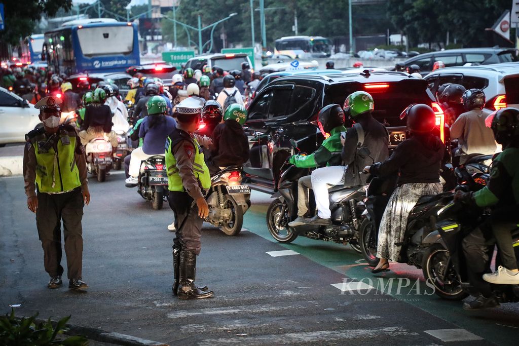 Polisi mengatur lalu lintas pada persimpangan jalan di kawasan Kuningan, Jakarta, Senin (3/7/2023). Bekerja sama dalam Project Green Light dengan Google, Dinas Perhubungan DKI Jakarta telah memasang teknologi kecerdasan buatan atau artificial intelligence (AI) di 20 simpang jalan sejak April 2023. 