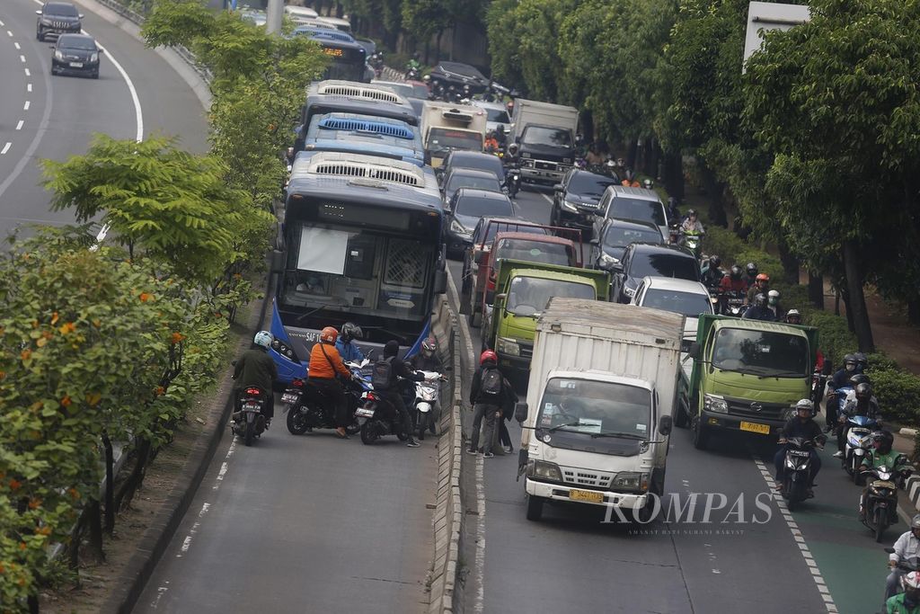 Pengendara bermotor membongkar separator jalur Transjakarta di Jalan Letjen S Parman, Slipi, Jakarta Barat, untuk menghindari razia petugas kepolisian di ujung jalur Transjakarta tersebut, Senin (29/5/2023). 