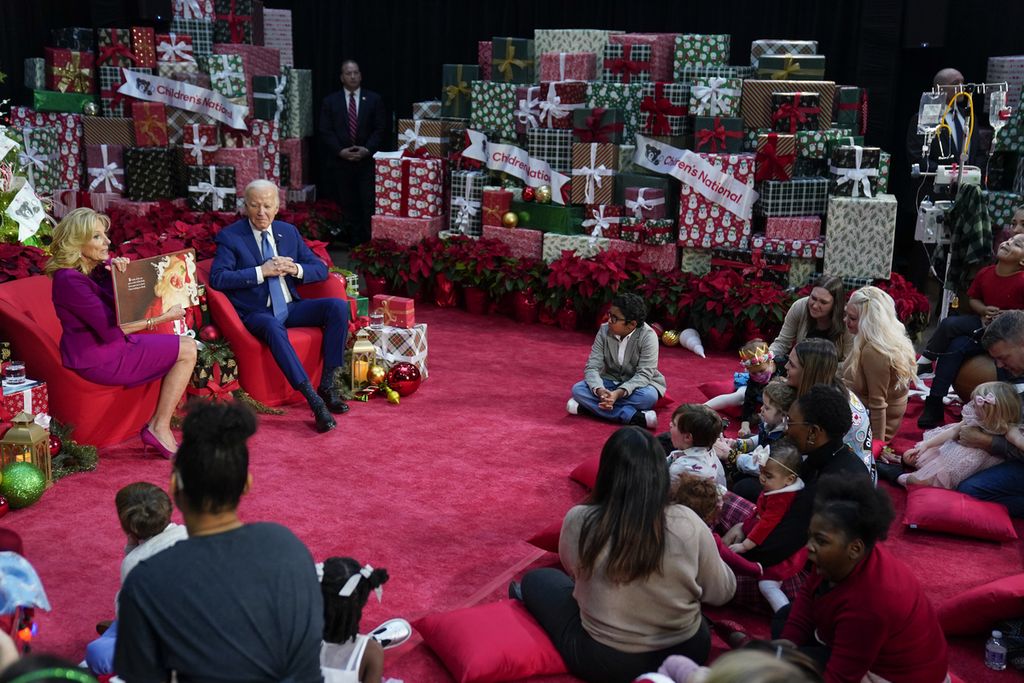 Ibu Negara AS Jill Biden didampingi Presiden Joe BIden membacakan kisah Natal berjudul "Twas the Night Before Christmas" di Rumah Sakit Nasional Anak-anak di Washington, Jumat (22/12/2023). (AP Photo/Evan Vucci)