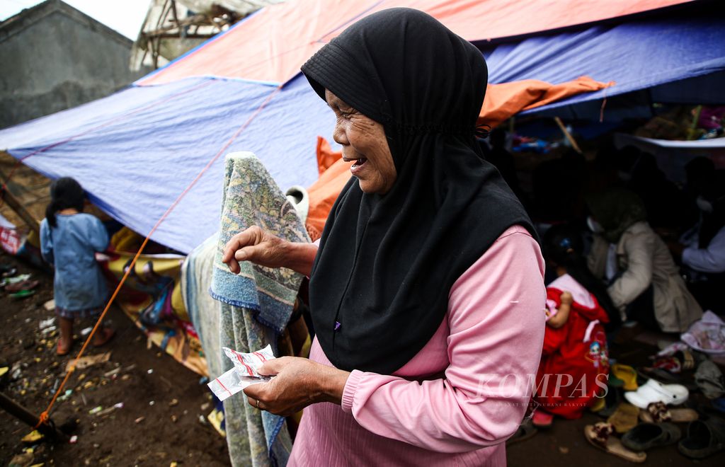 Seorang lansia menerima obat setelah menjalani pemeriksaan kesehatan oleh para relawan medis di tenda pengungsian di kampung Ciberem, desa Cikanyere, Kecamatan Sukaresmi, Kabupaten Cianjur, Jawa Barat, Minggu (27/11/2022).