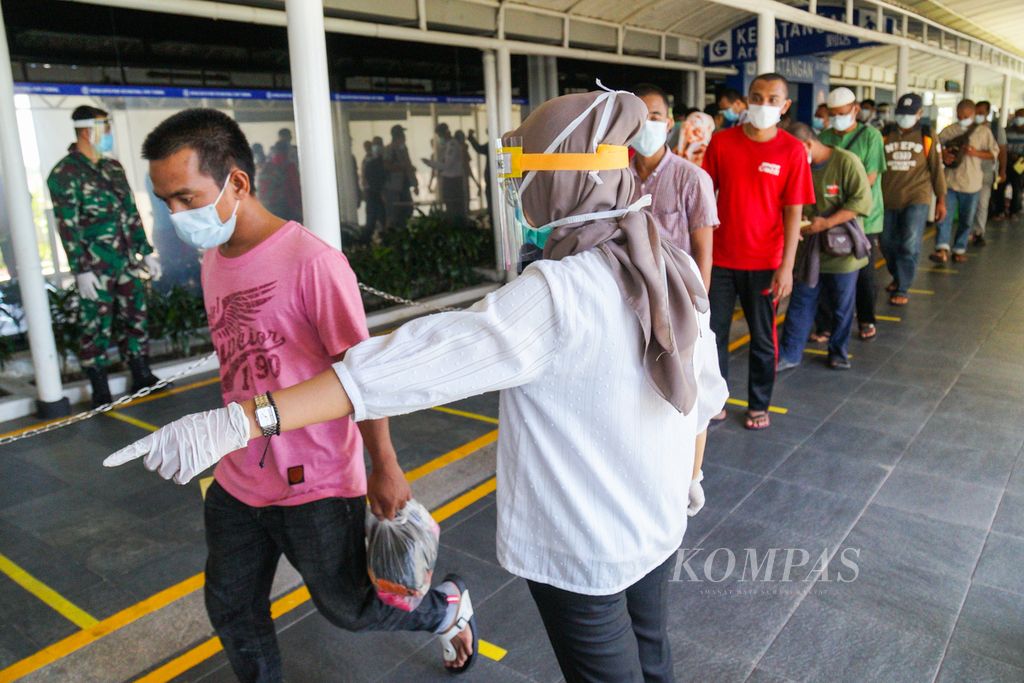Petugas Kantor Kesehatan Pelabuhan Kelas I Batam mengatur antrean ratusan pekerja migran Indonesia di Pelabuhan Internasional Batam Centre, Kota Batam, Kepulauan Riau, Kamis (21/5/2020).