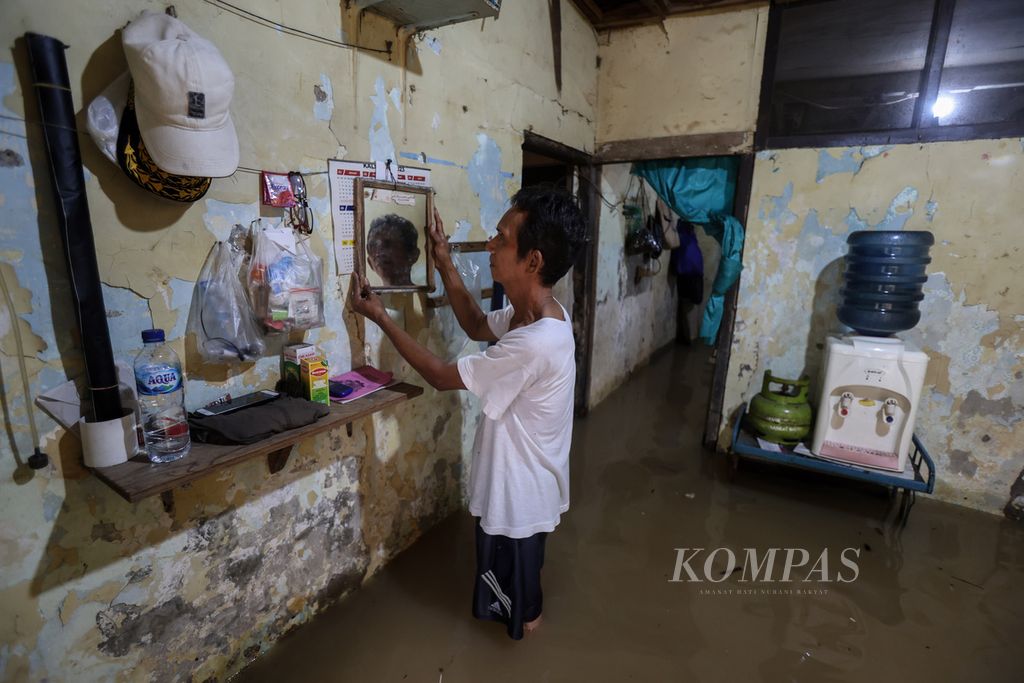 Warga merapikan barang-barang di rumahnya yang tergenang banjir di Kelurahan Kampung Melayu, Kecamatan Jatinegara, Jakarta Timur, Kamis (30/11/2023).
