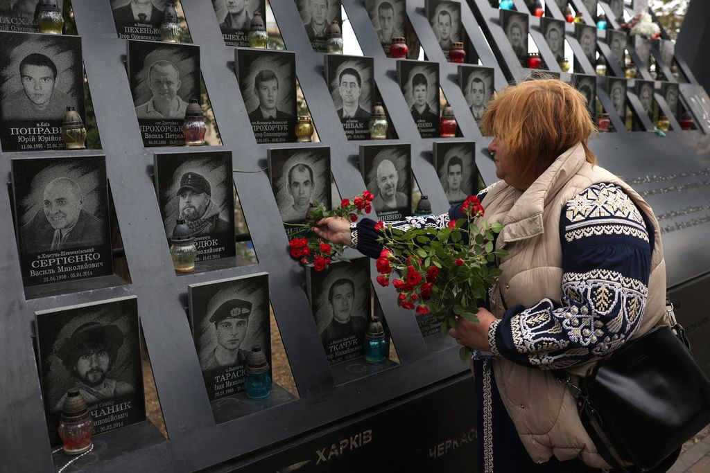 Seorang perempuan meletakkan bunga di Heavenly Hundred Heroes Memorial untuk memberi penghormatan kepada aktivis Maidan yang terbunuh dalam demonstrasi anti-pemerintah tahun 2014, menandai Hari Pembela Ukraina di Kyiv, Ukraina, 1 Oktober 2023.