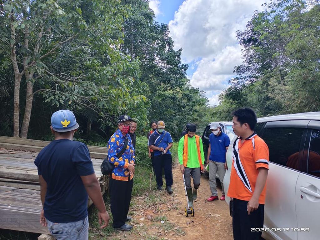 Salah satu saksi dari Dinas PUPR Kabupaten Lamandau, Kalimantan Tengah, Ronny Novian (kedua dari kiri berbaju biru), sedang melakukan uji konstruksi jalan di jalan usaha tani yang menjadi obyek perkara dalam kasus dugaan korupsi yang melibatkan Kades Kinipan.