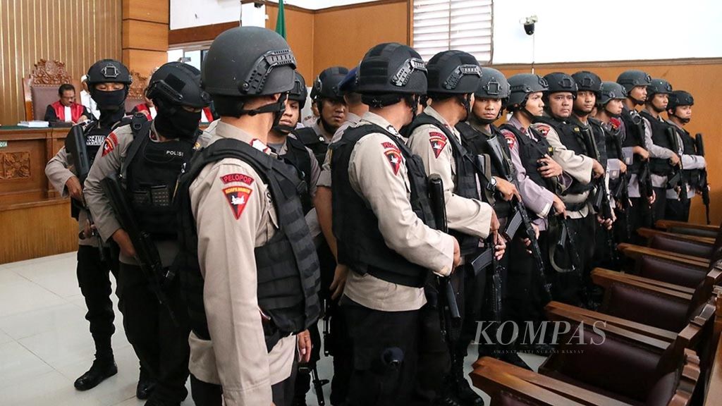 Polisi berbaris untuk menutup terdakwa kasus terorisme, Aman Abdurrahman, yang sujud setelah mendengarkan vonis dari majelis hakim di Pengadilan Negeri Jakarta Selatan, Jumat (22/6/2018). 