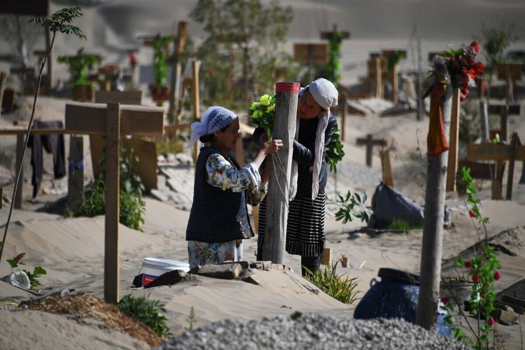 (FILE) Dalam file ini foto yang diambil pada tanggal 31 Mei 2019 memperlihatkan dua perempuan mendekorasi kuburan di kuburan Uighur di pinggiran Hotan di wilayah barat laut Xinjiang, Cina. (Foto oleh Greg Baker / AFP)