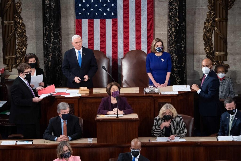 Ketua DPR Nancy Pelosi, politisi Demokrat dari California (kanan)  berdiri di samping Wakil Presiden Mike Pence di Kongres untuk menghitung perolehan suara di gedung Capitol di Washington, DC, Amerika Serikat, 6 Januari 2021.