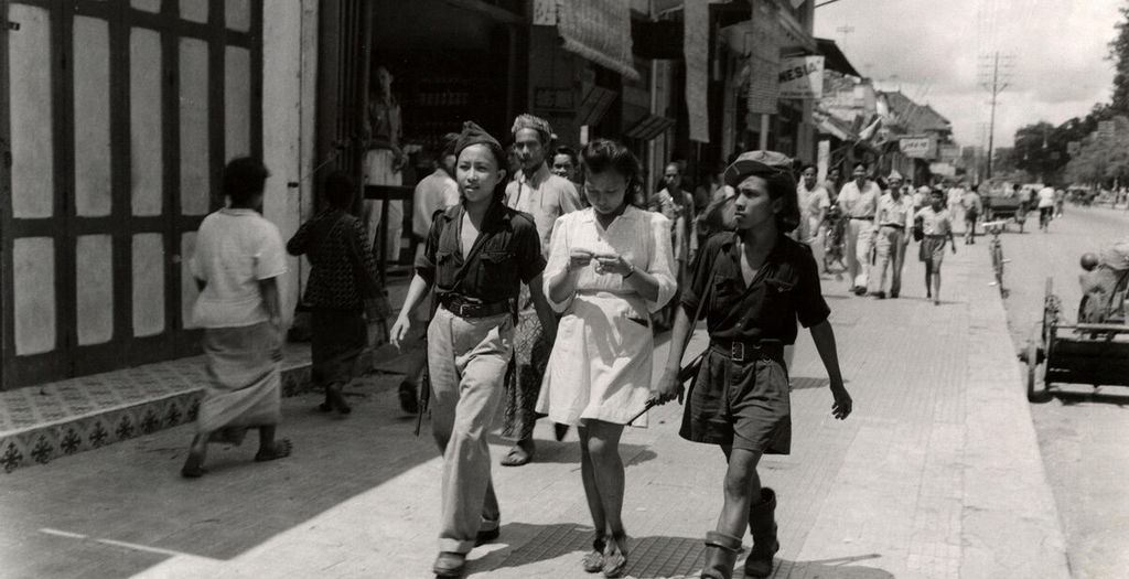 Tiga perempuan muda Indonesia di jalan. Dua di antaranya adalah relawan Republik Indonesia dari Sulawesi, anggota angkatan bersenjata muda KRIS, di Yogyakarta, Desember 1947. 