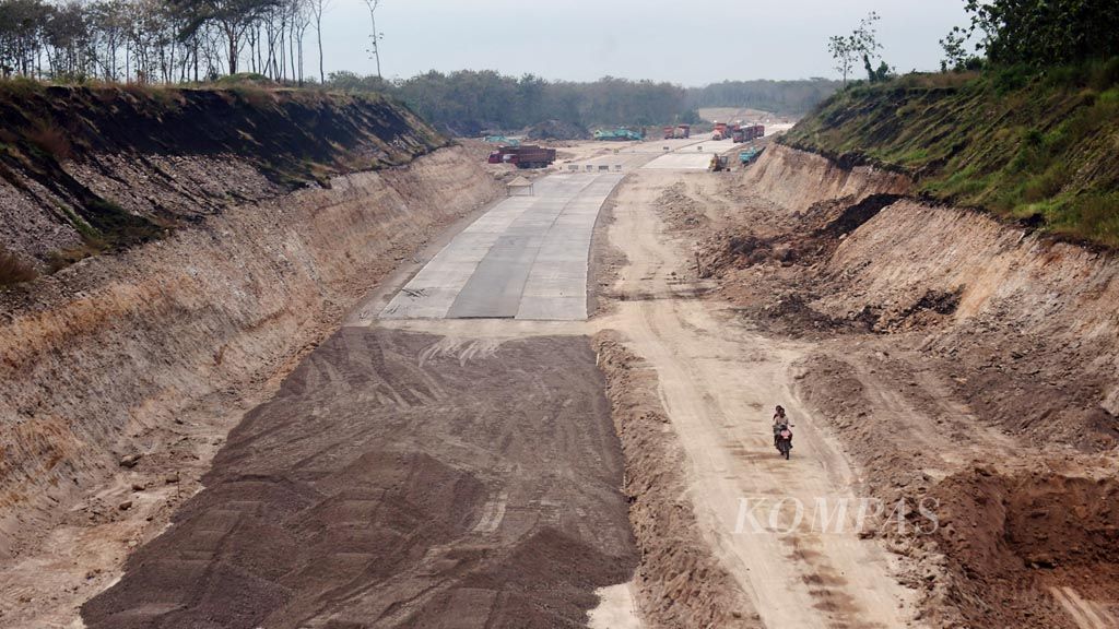 Pekerja melintasi proyek Tol Trans-Jawa antara Ngawi dan Kertosono di Kecamatan Saradan, Kabupaten Madiun, Jawa Timur, Jumat (26/5). Saat ini sejumlah proyek jalan tol dikebut pengerjaannya agar dapat digunakan pada musim mudik Lebaran tahun ini.