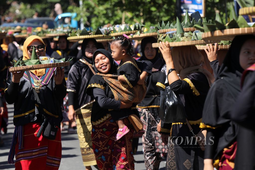 Seorang ibu menggendong anaknya saat mengikuti parade Nyiru Jaja Bejangkongan di Desa Pringgasela Selatan, Kecamatan Pringgasela, Lombok Timur, Nusa Tenggara Barat, Rabu (20/12/2023). 