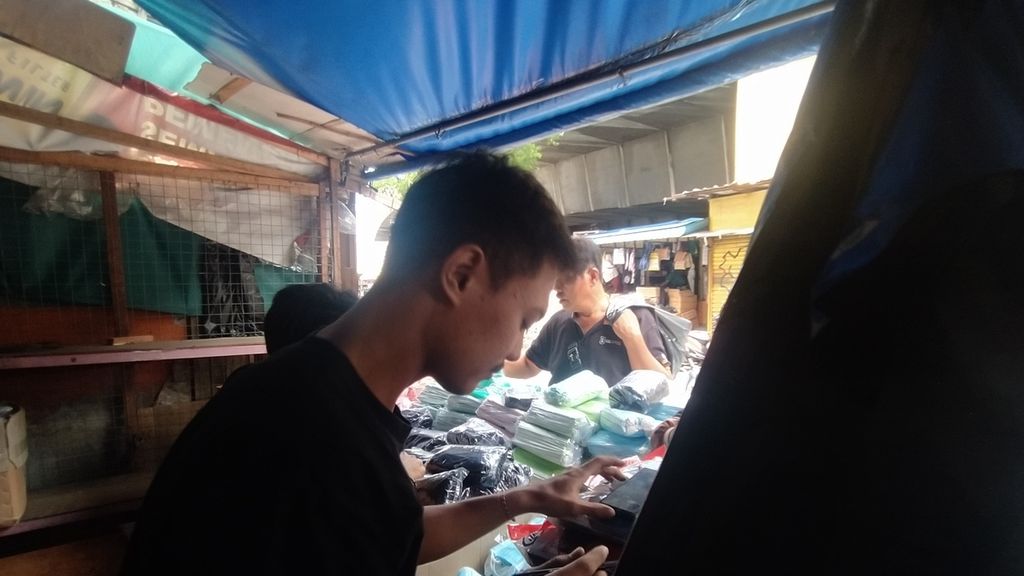 Arif Mustofa (22) kembali berdagang di seberang kiosnya yang terbakar, di kawasan Pasar Pagi Asemka, Kelurahan Pinangsia, Taman Sari, Jakarta Barat, Senin (21/11/2022).