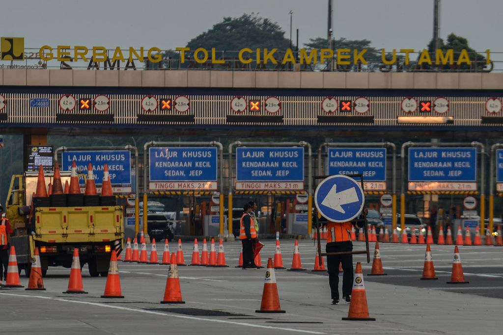 Petugas mengangkat rambu lalu lintas di Gerbang Tol Cikampek Utama, Karawang, Jawa Barat, Senin (24/4/2023). Rekayasa lalu lintas satu arah atau one way dan contraflow mulai diberlakukan kepolisian untuk mengurangi kemacetan saat arus balik Lebaran 2023.