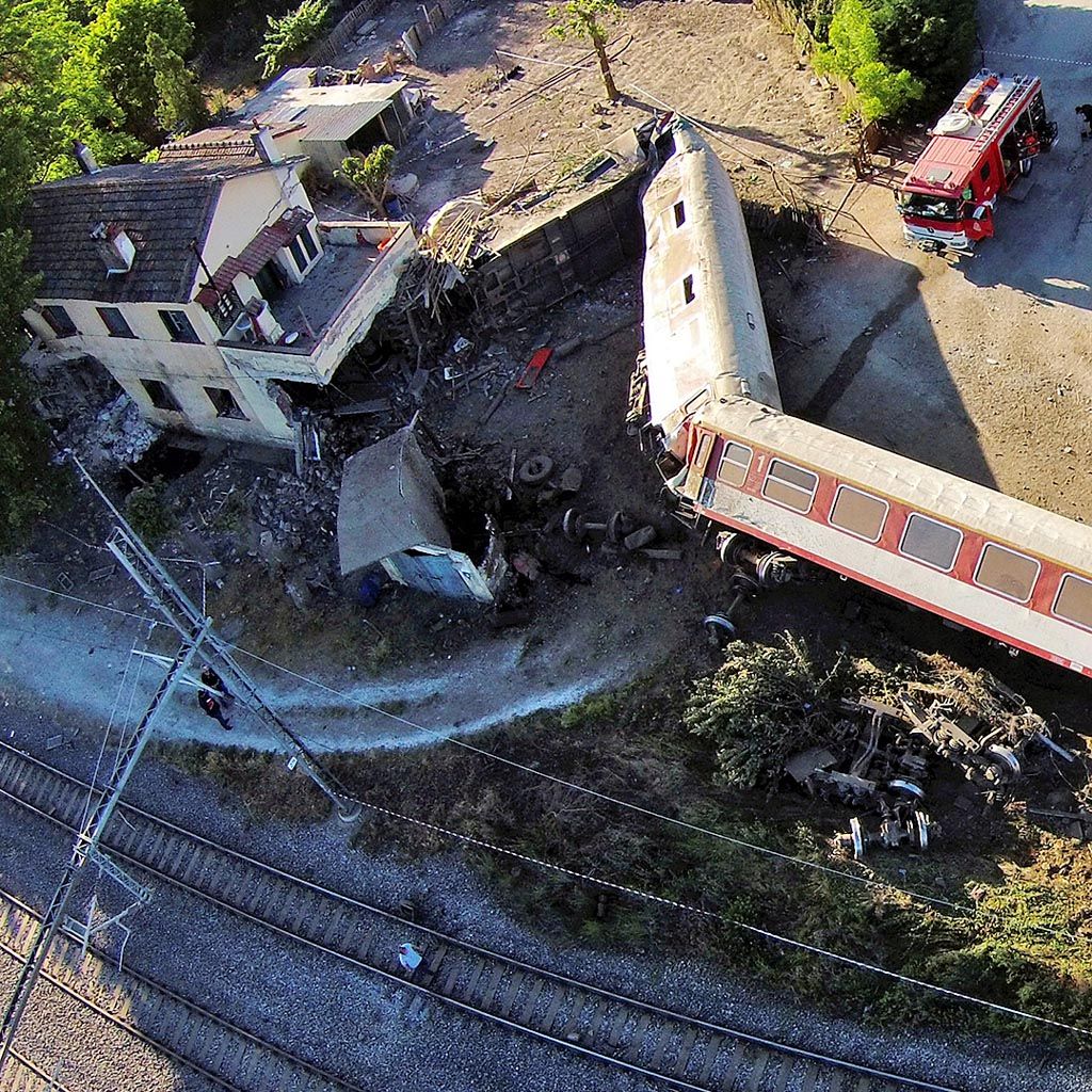 Sebuah rangkaian kereta terguling setelah tergelincir dan menabrak rumah di kota Adendro, Yunani, Minggu (14/5). 