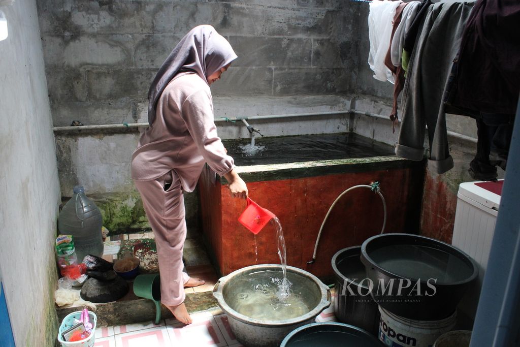 Rini (22), memasukkan air dari bak ke ember-ember kecil di kamar mandi rumahnya di Kampung Karamat, Desa Sukamulya, Kecamatan Cugenang, Cianjur, Jawa Barat, Rabu (28/8/2024). Dia kini lebih tenang menyiapkan kelahirannya yang tinggal beberapa hari lagi karena memiliki banyak persediaan air bersih.