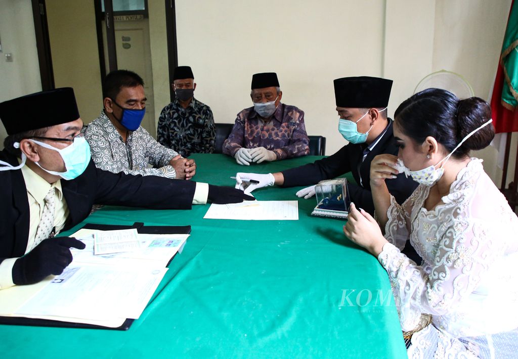 Penghulu, saksi, serta pasangan Rizki dan Mutiara mengenakan masker saat menjalani prosesi pernikahan di Kantor Urusan Agama (KUA) Kecamatan Gambir, Jakarta Pusat, Minggu (5/4/2020). 