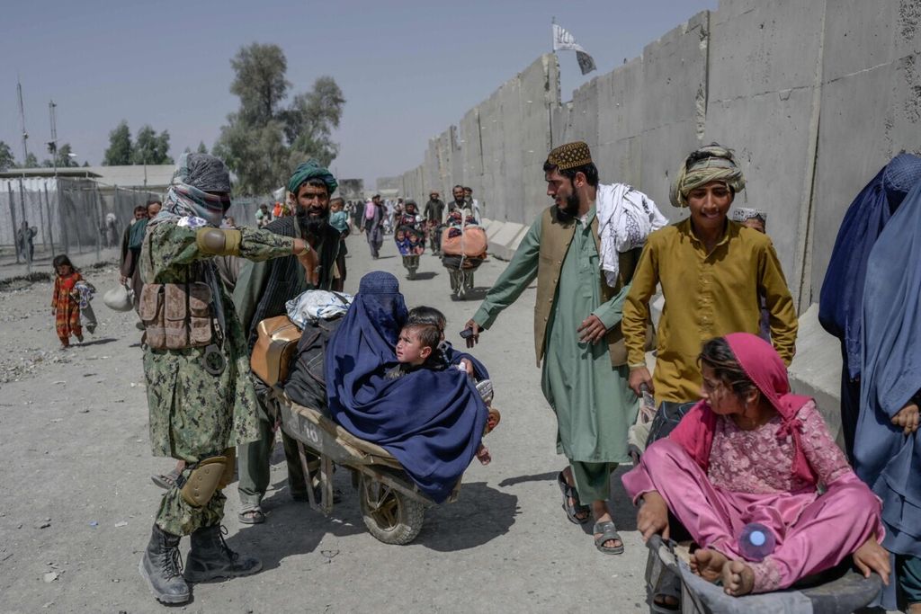 Warga Afghanistan dengan membawa barang mereka bergegas melintasi perbatasan menuju Pakistan di Spin Boldak pada 25 September 2021. Ribuan warga Afghanistan meninggalkan rumah mereka untuk mengungsi setelah Afghanistan jatuh ke tangan Taliban.