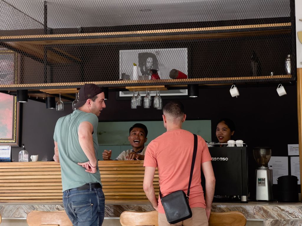 Dua karyawan di restoran JM Hotel Kuta, Pujut, Lombok Tengah, Nusa Tenggara Barat, Senin (25/7/2022), berbincang dengan wisatawan asing yang datang berlibur ke kawasan tersebut. Seiring makin menggeliatnya kawasan Mandalika, masyarakat juga tak ingin sekadar menonton dan saat ini mulai mengambil bagian.