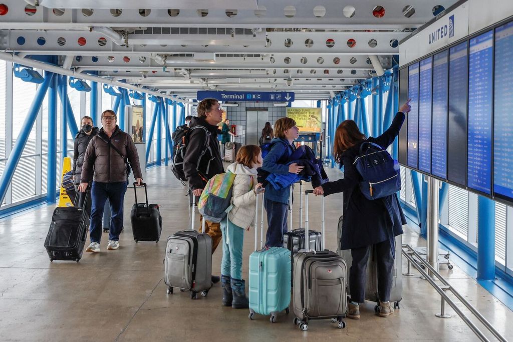 Sejumlah penumpang tengah mengecek status penerbangan saat mereka tiba di terminal maskapai United Airlines, Bandara  Internasional O'Hare International, Chicago pada Kamis (22/12/2022).