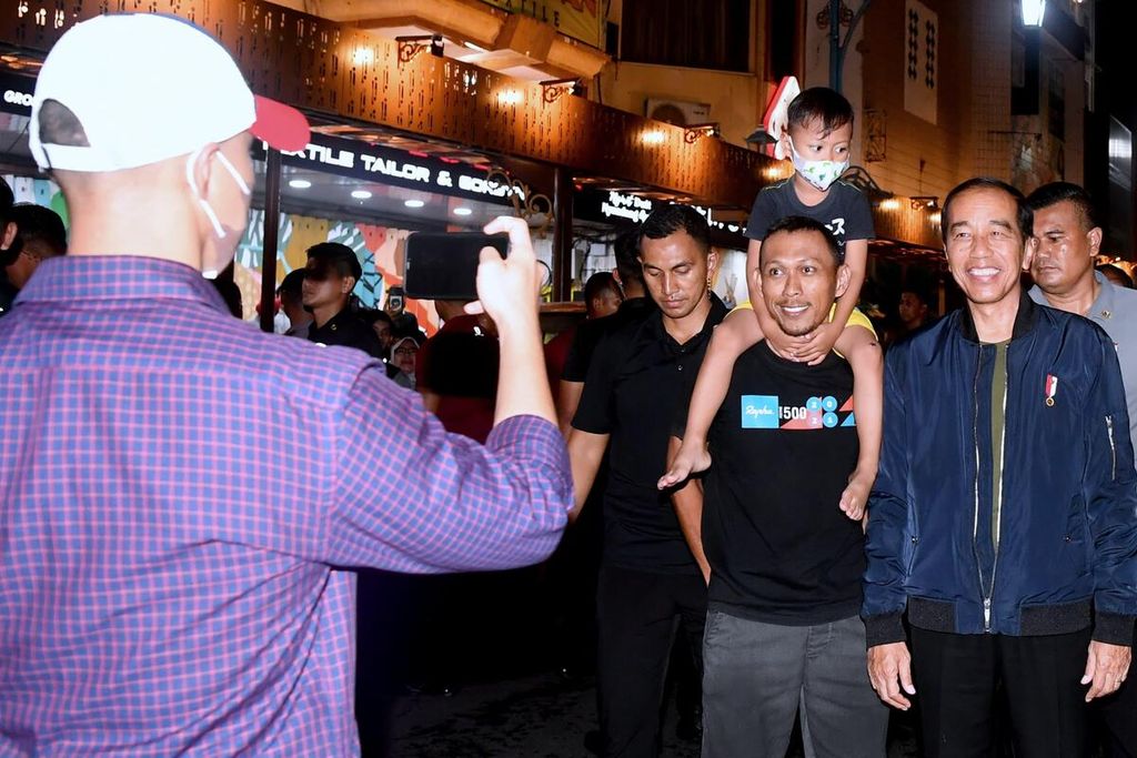 Presiden Joko Widodo saat berfoto bersama warga pada malam menjelang pergantian tahun di Kota Surakarta, Jawa Tengah, Minggu (31/12/2023).