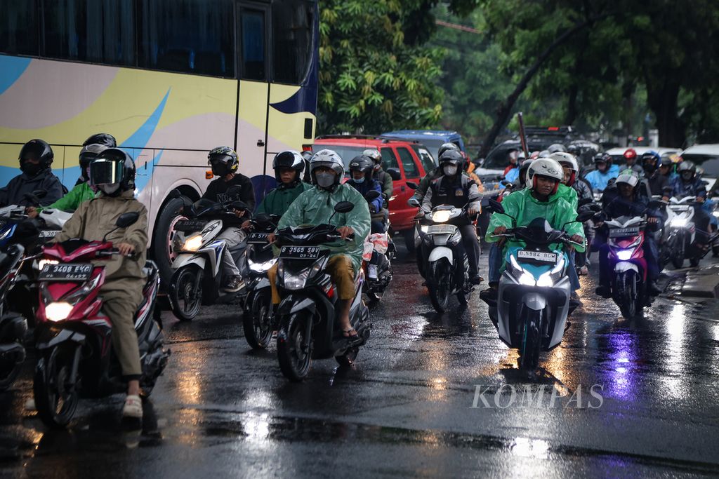 A group of motorcyclists wearing raincoats drive through the Tanjung Barat area in South Jakarta on Thursday (23/11/2023). Jakarta is currently transitioning from the dry season to the rainy season, also known as pancaroba. The public should be cautious because the pancaroba period has the potential to cause extreme weather conditions, such as heavy rain accompanied by lightning and strong winds.