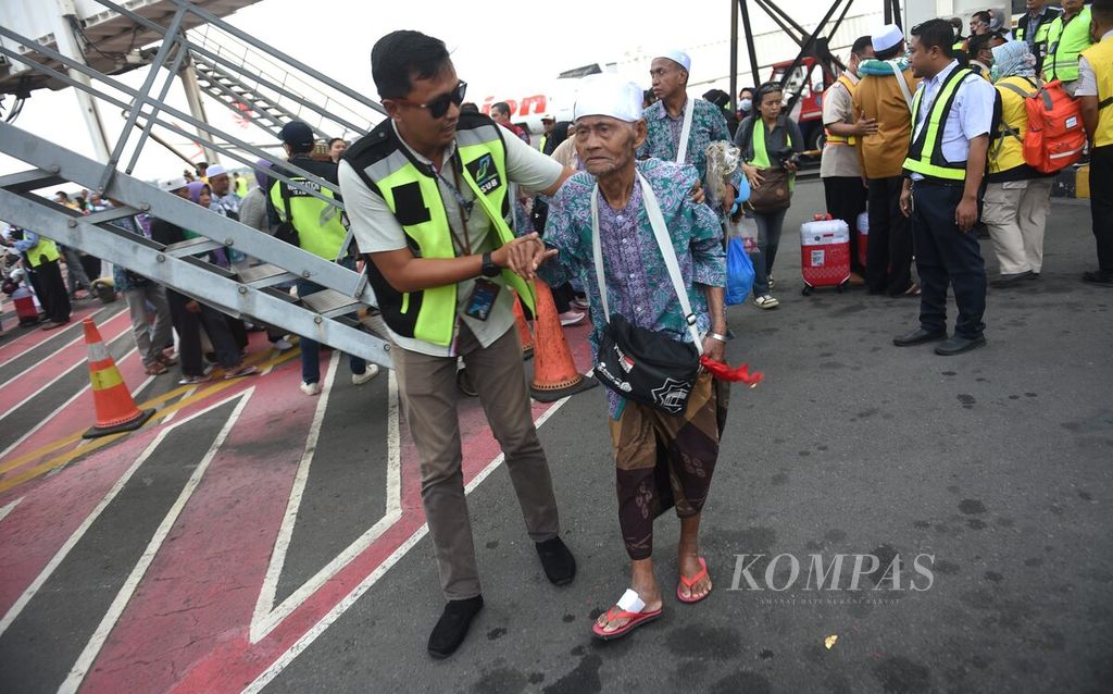 Petugas membantu jalan anggota jemaah haji kloter 1 asal Kabupaten Bangkalan yang baru tiba di Bandara Juanda Surabaya, Sidoarjo, Jawa Timur, Selasa (4/7/2023).