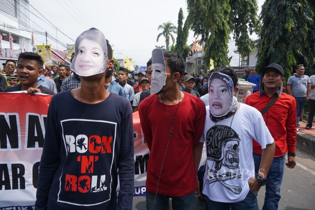 Demonstran menggunakan topeng saat berunjuk rasa di depan kantor Sentra Penegakan Hukum Terpadu (Gakkumdu) Provinsi Lampung, Selasa (10/7/2018). 