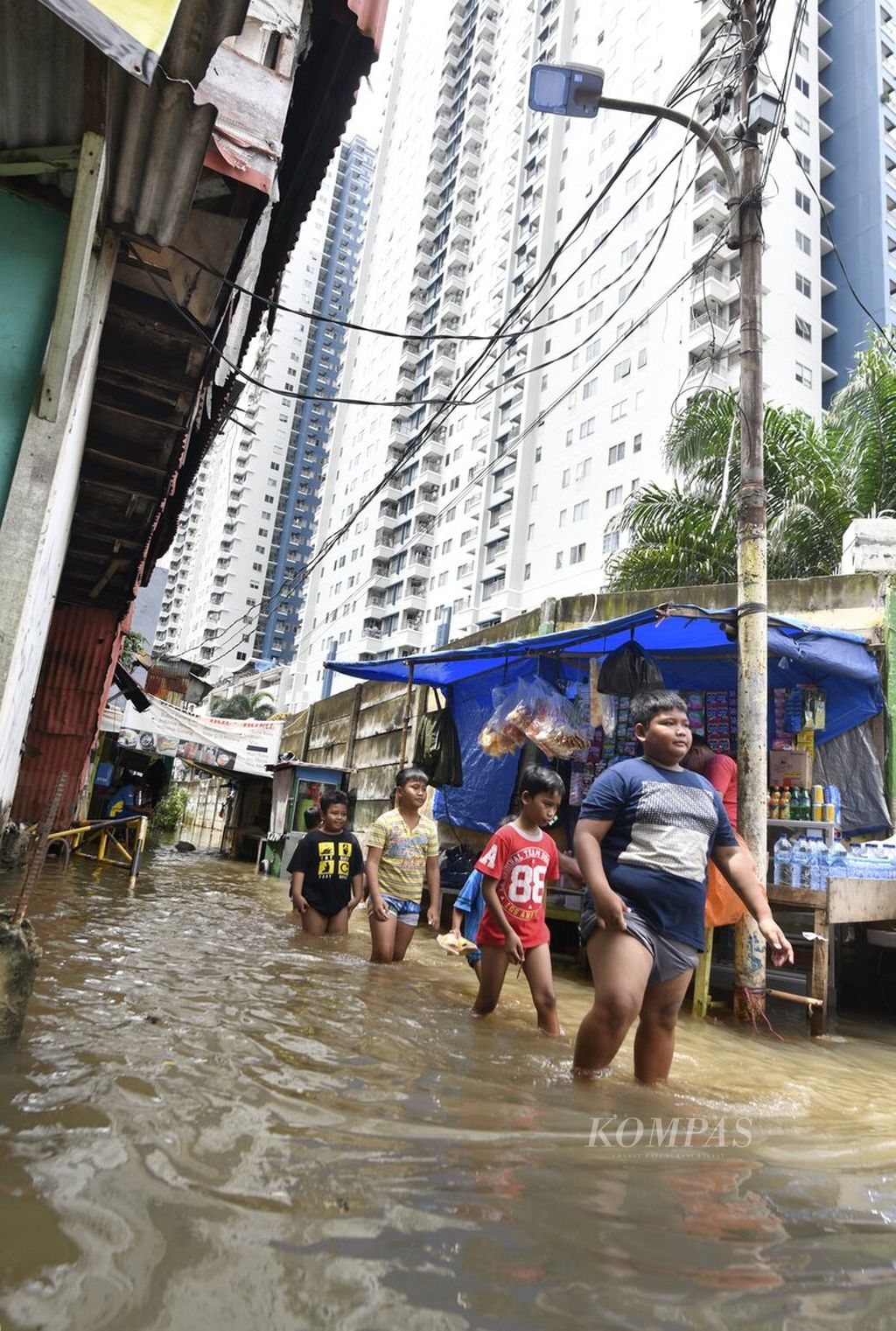 Anak-anak berjalan melewati banjir di Jalan Karet Pasar Baru Timur, Tanah Abang, Jakarta Pusat, Minggu (23/2/2020). Sejumlah kawasan di Jakarta kembali dilanda banjir setelah hujan deras mengguyur Jakarta.