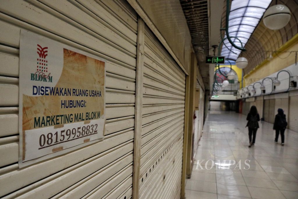 Warga melalui lorong di sebuah pusat perbelanjaan di kawasan Blok M, Jakarta, yang telah ditinggal sebagian besar penyewa dan pengunjungnya, Senin (24/7/2023). 