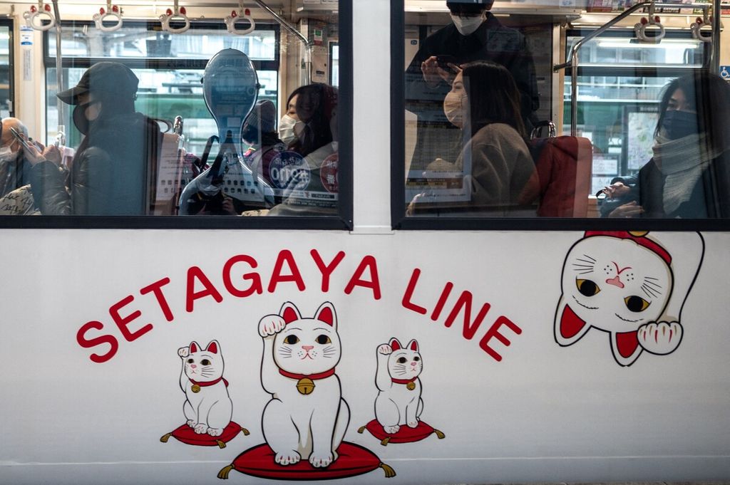 Penumpang trem Setagaya Line yang didekorasi dengan <i>maneki-neko</i> atau kucing yang melambai di Tokyo, 30 Januari 2022. 