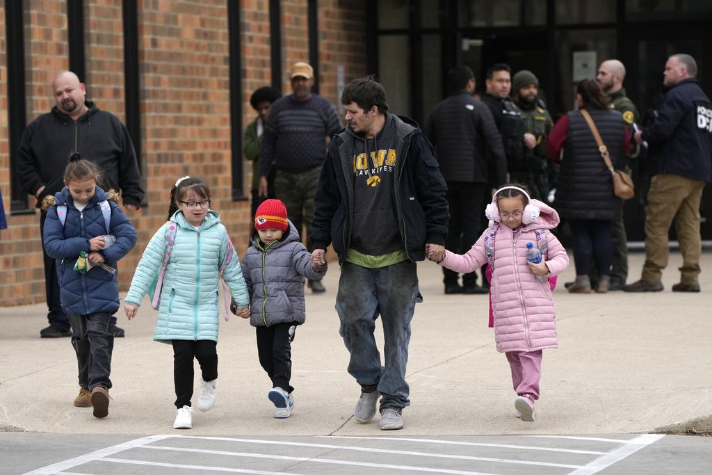 Seorang laki-laki dan anak-anak meninggalkan gedung Komunitas McCreary setelah dipertemukan kembali usai penembakan di Sekolah Menengah Perry, 4 Januari 2024, di Iowa, Amerika Serikat.