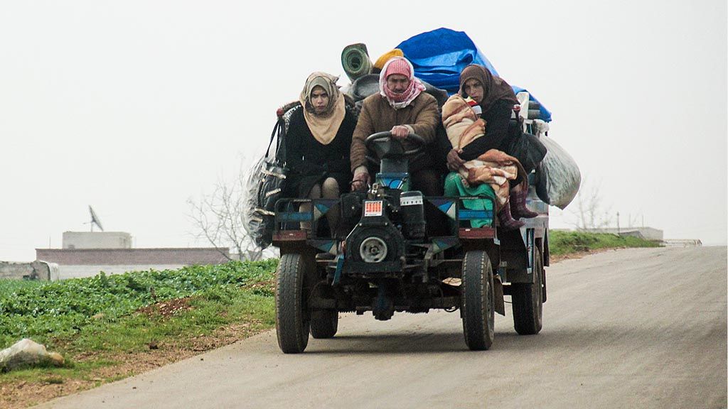 Satu keluarga di Suriah mengungsi setelah wilayah tempat tinggal mereka dihantam serangan udara. Mereka mengangkut harta benda mereka dengan kendaraan perlengkapan pertanian yang melaju di jalan raya dekat kota Tayyibat al-Imam, Provinsi Hama, Suriah, dalam foto yang dirilis pada Rabu (22/3). 