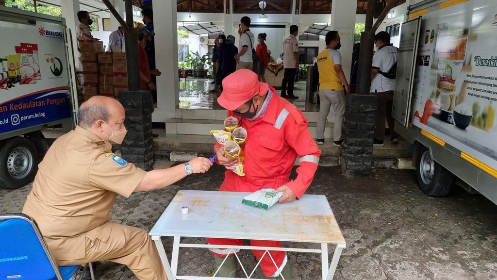 Salah satu warga ditandai dengan tinta oleh petugas saat operasi pasar di Kantor Kecamatan Gedebage, Kota Bandung, Jawa Barat, Senin (7/3/2022). Tanda tinta ini untuk memastikan warga tidak membeli barang-barang untuk kedua kali.