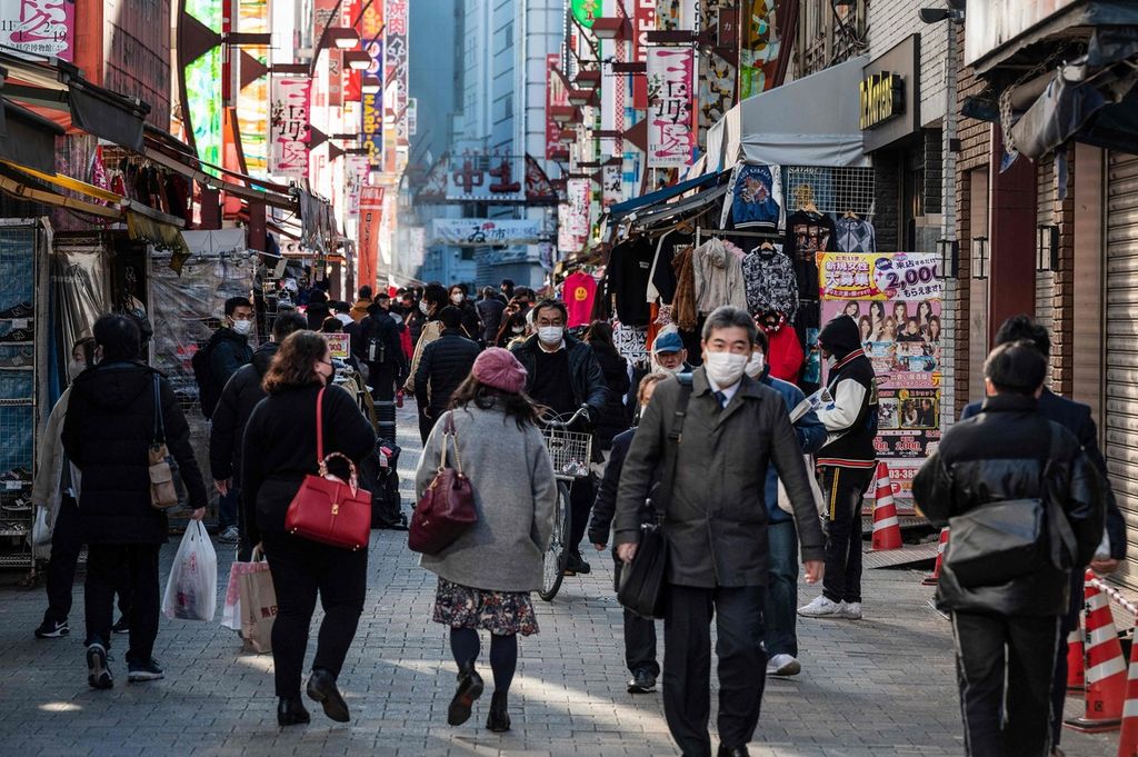 Seorang pekerja melewati pasar Ueno, Tokyo pada Desember 2022. Sebagian besar warga Jepang terbiasa bekerja dalam waktu panjang di satu tempat kerja. 