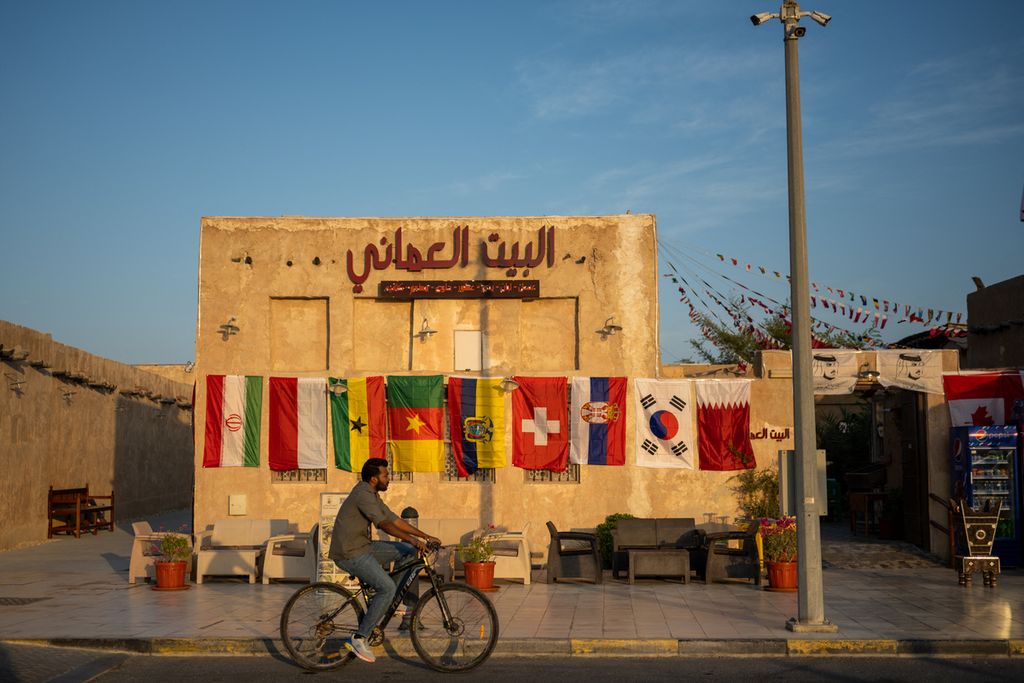 A man rides a bicycle past a restaurant adorned with FIFA World Cup playing countries flags in a market area in Doha on November 3, 2022, ahead of the Qatar 2022 FIFA World Cup football tournament. 