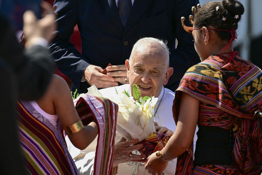 Paus Fransiskus disambut dua anak kecil yang memberi bunga saat turun dari pesawat di Bandara Internasional Presiden Nicolau Lobato, Dili, Timor Leste, Senin (9/9/2024).