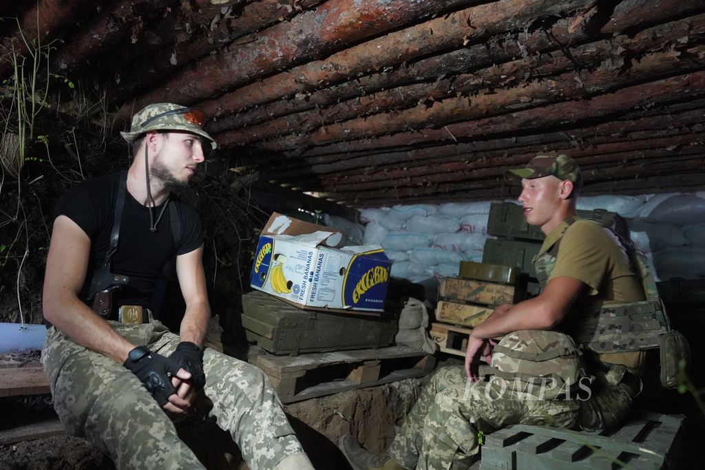 Dua tentara Ukraina sedang berada di dalam parit di salah satu lokasi di sekitar garis depan pertempuran di wilayah timur Ukraina, Jumat (8/7/2022). Perang Ukraina-Rusia di garis depan lebih banyak diwarnai dengan pertempuran artileri dan serangan udara. Para prajurit menggunakan parit untuk berlindung dari serangan artileri.