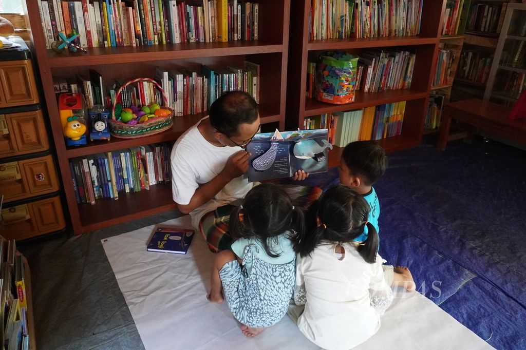 Yulianto (31), a listeration activist, reads story books to children who visit the Bintang Reading House, Sumberjosari Village, Karangrayung District, Grobogan Regency, Central Java, Saturday (14/5/2022). The reading house is one of four reading houses that he manages in Grobogan.